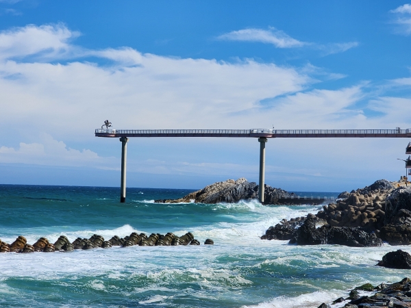 바다위로 쑥 뻗어나온 등기산스카이워크 뒤편으로 후포 갓바위가 보인다.